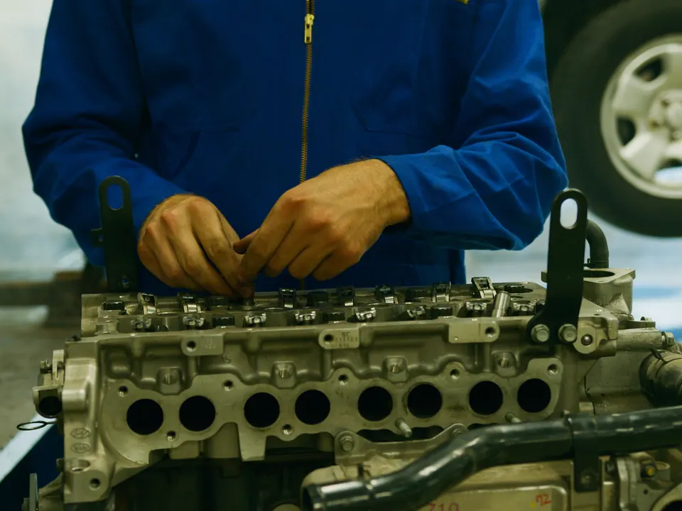 Monteur in blauwe overall werkt aan een losstaande motor in een werkplaats